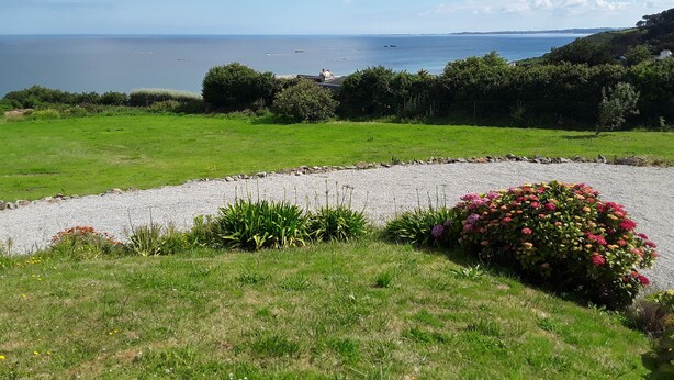 A coastal landscape with a grassy area, a gravel path, and a flower bed. - HOLIDAY HOUSE WITH STUNNING SEA VIEWS (Locquirec)