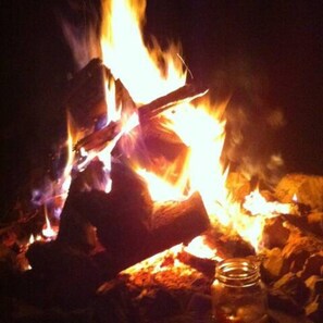 A campfire with logs and a glass jar nearby. - Peace and quiet of country living within minutes of city amenities.   (Scottsville)