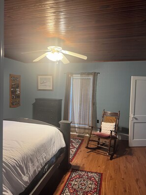 A bedroom with a bed, a wooden chair, a dresser, a ceiling fan, and a window with curtains. - Peace and quiet of country living within minutes of city amenities.   (Scottsville)