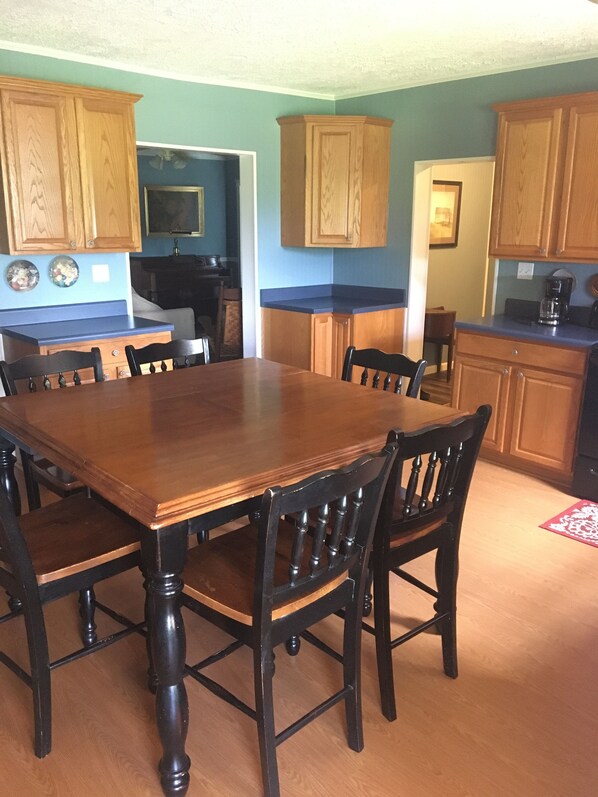 Comedor con mesa y sillas de madera, armarios de madera y encimera azul.