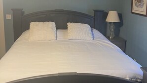 Ein Schlafzimmer mit Bett, Nachttisch, Lampe und einem gerahmten Bild an der Wand.