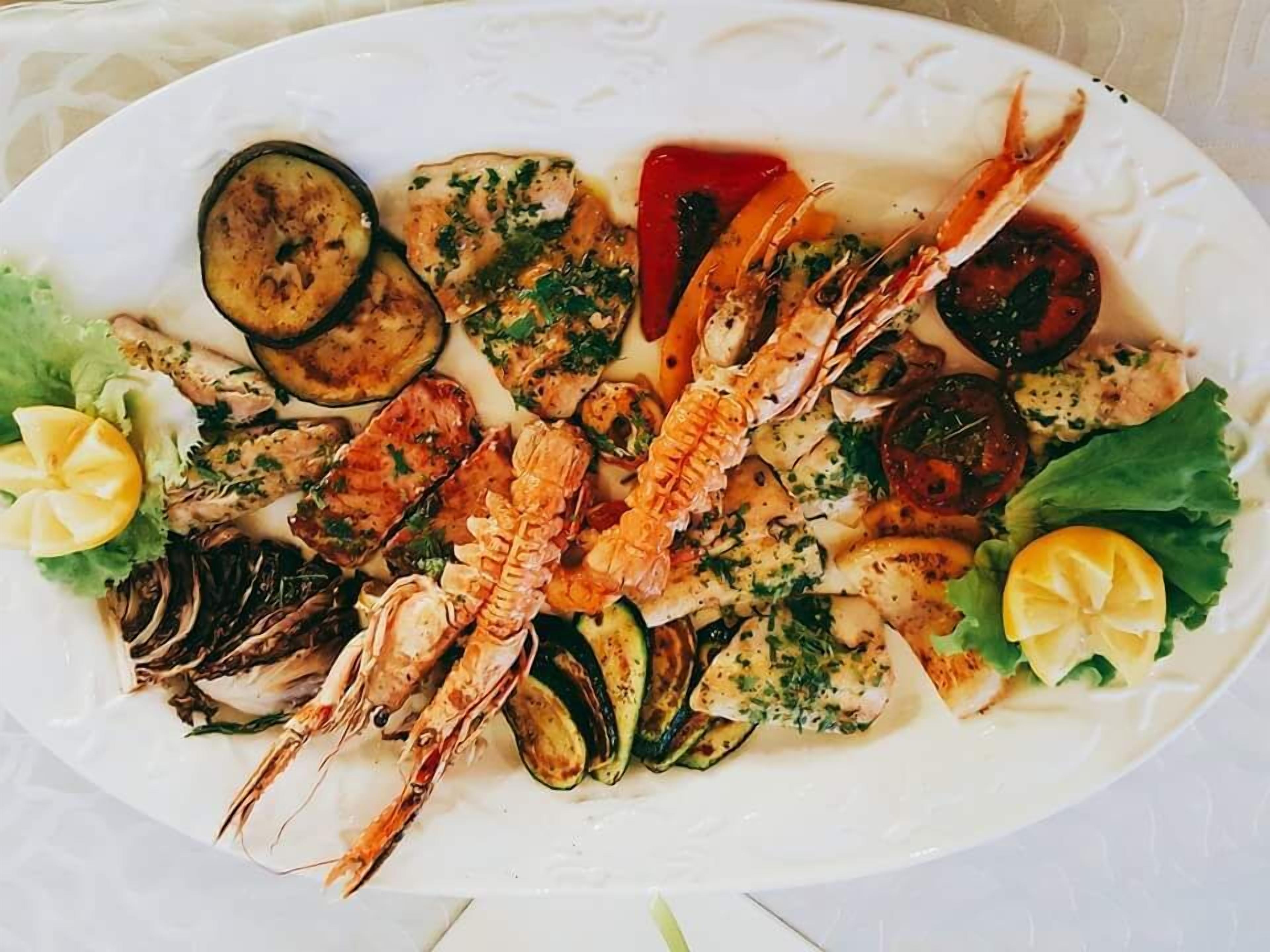 Eine Fischplatte mit gegrilltem Gemüse und Zitronenscheiben.