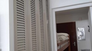 A room with a closed door, a small window, and a bed with a wooden headboard.