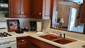 Una cocina con armarios de madera, estufa blanca, fregadero y cafetera.