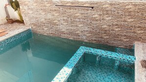 A swimming pool with a stone wall and tiled steps.