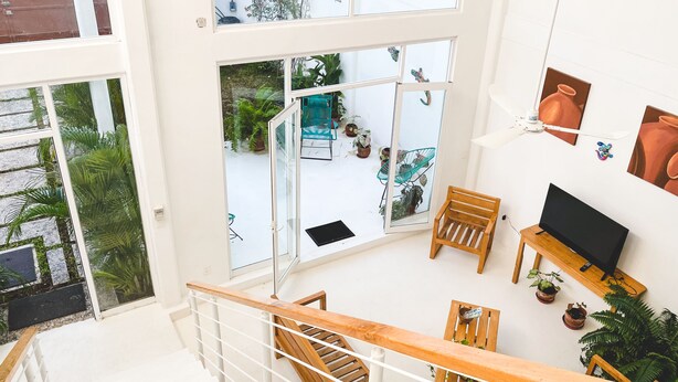 A modern interior with a staircase, wooden furniture, a TV on a stand, and potted plants.