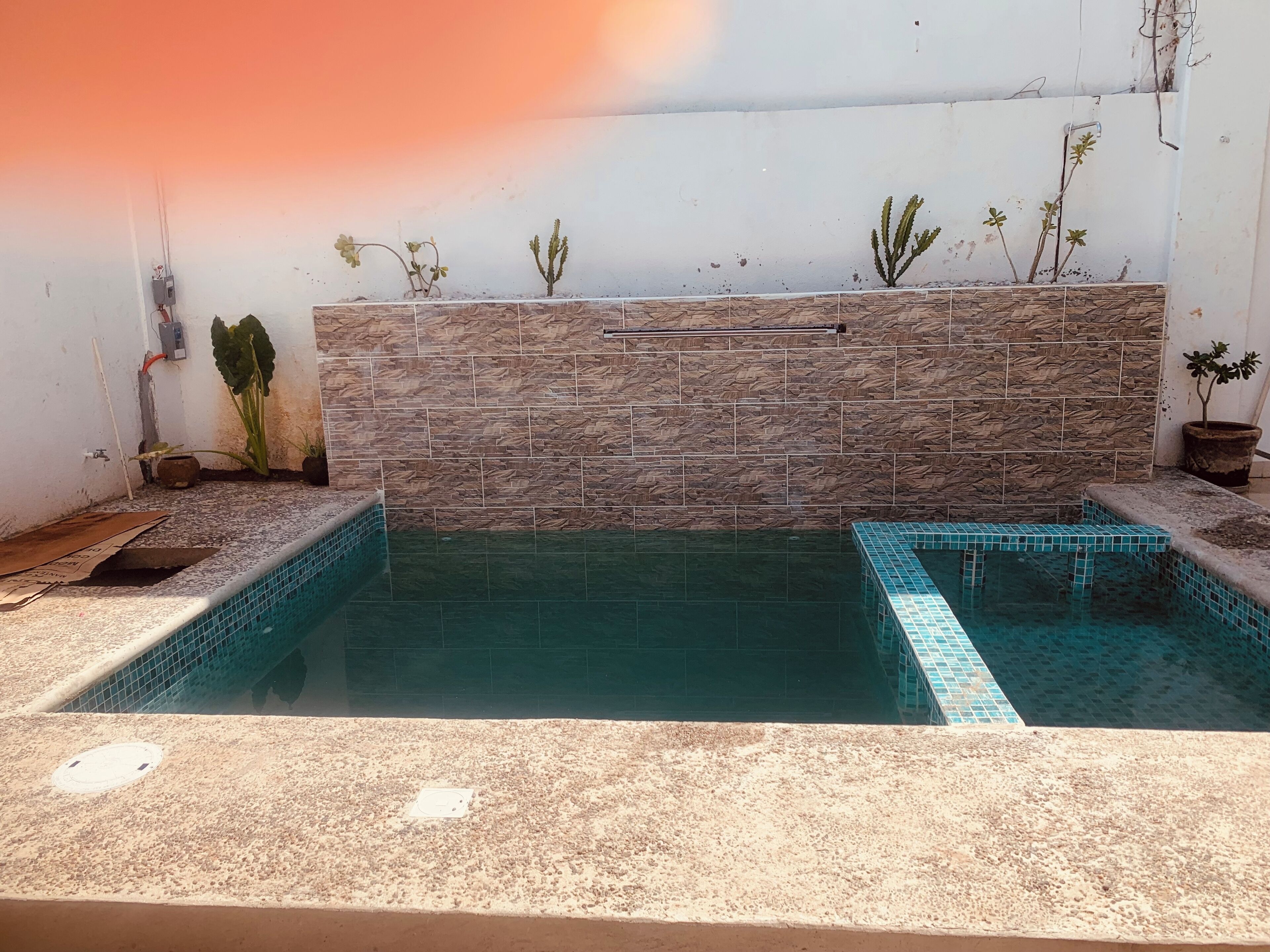A swimming pool with a stone wall and tiled steps.
