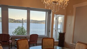 A dining area with a glass table surrounded by chairs, a chandelier, and large windows offering a view of a lake. - Stunning views of Lake Washington (Seattle)