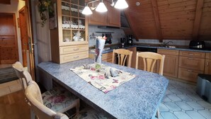 Eine Küche mit Holzausstattung, einer Arbeitsplatte aus Granit und einem Essbereich mit Stühlen und einem Tisch.