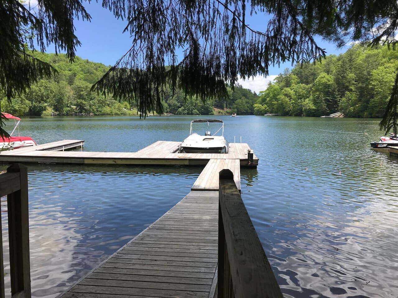 A wooden dock extending into a calm lake surrounded by lush greenery.