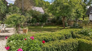 Un jardin agrémenté de diverses plantes et fleurs, un mur de pierre et une clôture en bois.