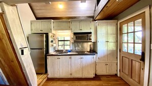 Une cuisine avec des meubles de rangement en bois, un réfrigérateur, un four à micro-ondes et un évier.
