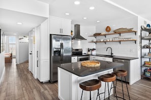 A modern kitchen with white cabinets, stainless steel appliances, and a central island with stools.