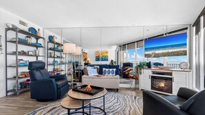 Een moderne woonkamer met een open haard, een bank, een salontafel en een groot raam met uitzicht op het strand.