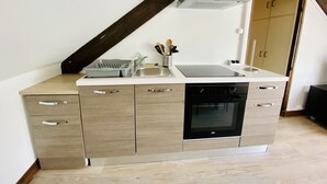 Een compacte keuken met een inbouwoven, een spoelbak en een houten aanrecht.