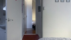 Una habitación de hotel con una cama, una puerta que da a un baño y un pequeño pasillo.