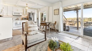 Een moderne keuken met witte kasten, een eethoek met een ronde tafel en stoelen, en een grote schuifpui die leidt naar een terras.
