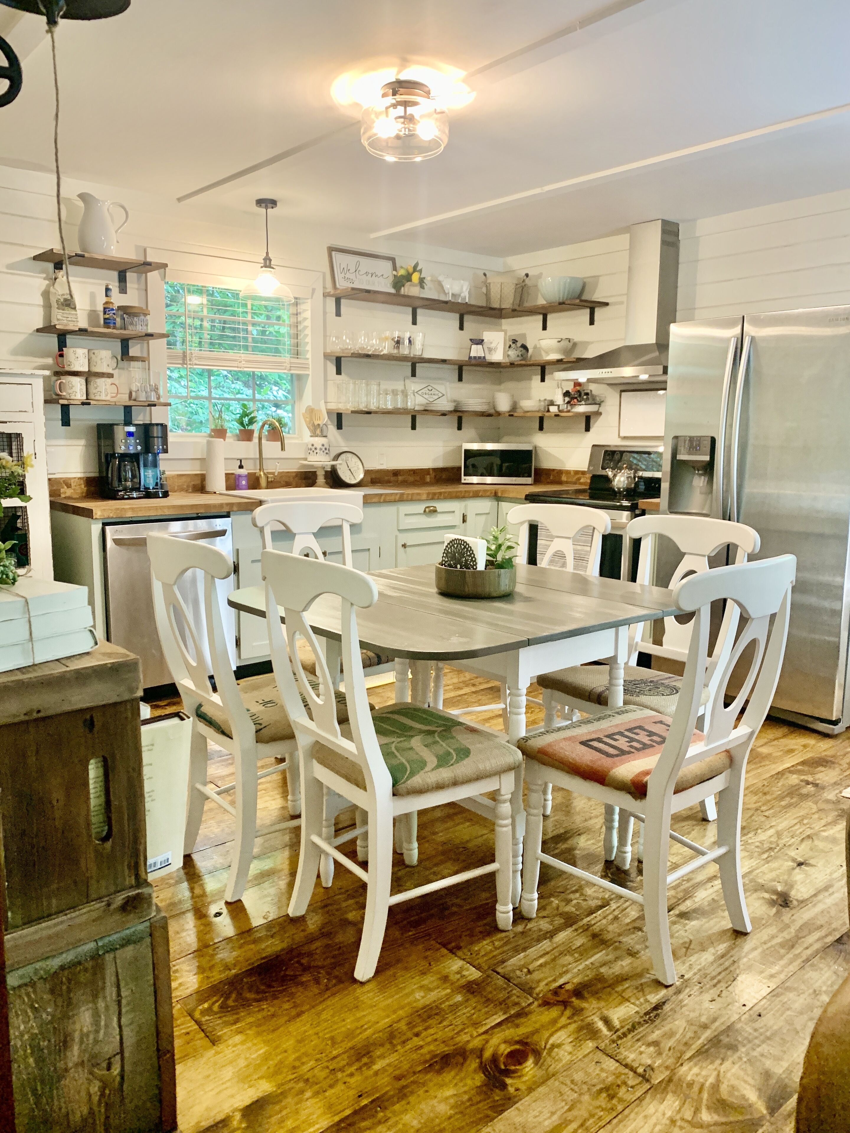 A modern kitchen with white cabinetry, wooden countertops, and a central island with chairs.
