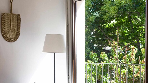 A living room with a grey sofa, patterned cushions, a wooden coffee table, and a view of a balcony with greenery. - Tourist accommodation Rurality Home C (Alberca, La)
