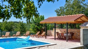 A swimming pool with lounge chairs and a covered seating area.