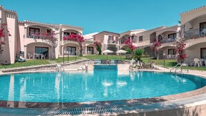 Een resort met een centraal gelegen zwembad, meerdere balkons en buitenzitplaatsen.