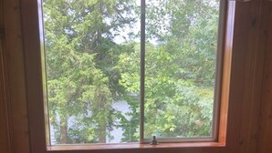 A room with wooden paneling and a window with a view of trees and a body of water. - Single Family Cottage Perfect for Families with Kids Charm and Sunset Included (McKellar)