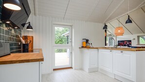 Uma cozinha moderna com armários brancos, bancada de madeira e luminárias pendentes pretas.