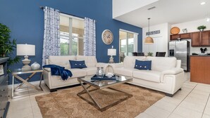 Un salon moderne avec un canapé blanc, une table basse en verre et un mur d’accent bleu.