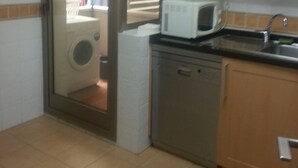 A compact kitchen with a microwave, sink, and a washing machine. - Paseo Marítimo Antonio Banderas (Málaga)