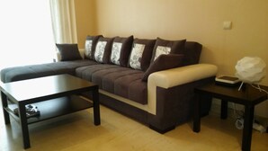 A modern living room with a sectional sofa, a coffee table, and a side table with a lamp. - Paseo Marítimo Antonio Banderas (Málaga)