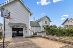 A residential property with a basketball hoop, a garage, and a wooden deck. - Inn Denial - Unmatched Oceanfront Elegance! (Bald Head Island)