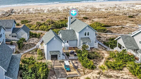 A coastal residential area with houses, a beach, and a lifeguard tower. - Inn Denial - Unmatched Oceanfront Elegance! (Bald Head Island)