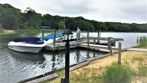 Un quai avec des bateaux, une jetée en bois et une personne debout sur le quai.