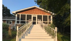 Une maison à deux étages avec un porche à l’avant, un escalier et une grande fenêtre à l’avant.