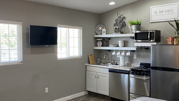 A modern kitchen with white cabinets, stainless steel appliances, and a ceiling fan. - Home on the Range (Hurricane)