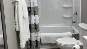 A bathroom with a shower, toilet, and a mirror. - Home on the Range (Hurricane)
