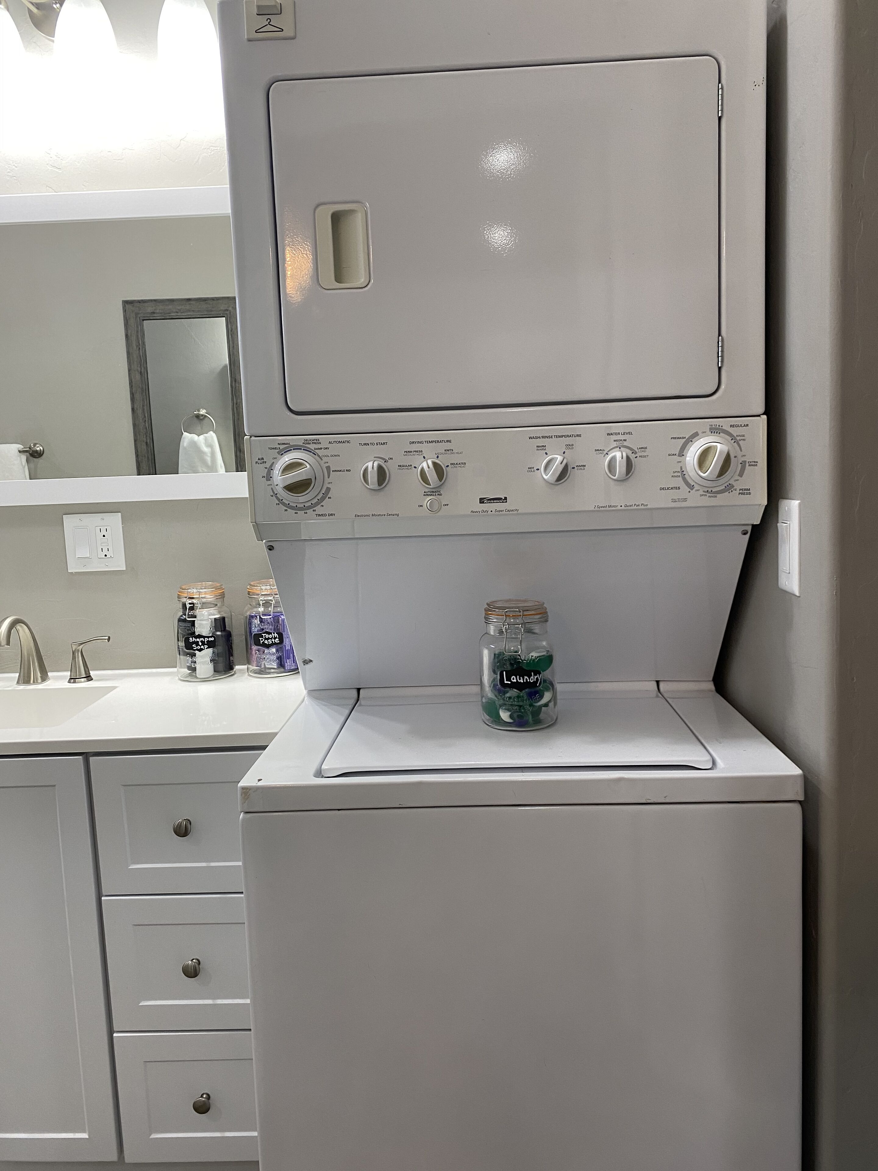 Une machine à laver compacte, de couleur blanche, dotée de plusieurs boutons de commande et d’un petit compartiment de rangement.