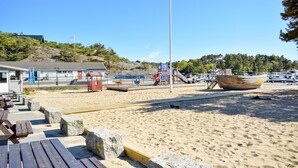 Een strand met een houten boot, picknicktafels en een redderstation.