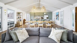 Amplia sala de estar con un sofá modular gris, una mesa de comedor de madera e iluminación colgante.