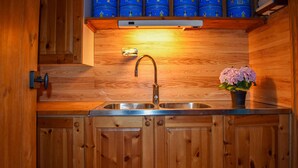 Una cocina de madera con un lavamanos de acero inoxidable, armarios de madera y una planta en maceta.
