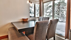 Ein Essbereich mit einem dunklen Holztisch, gepolsterten Stühlen und einem Korbwäsches auf dem Tisch.