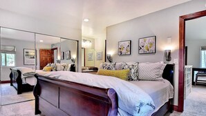 Ein Schlafzimmer mit einem großen Bett, einem Schminktisch, einem Spiegel und Bildern an der Wand.