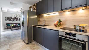 A modern kitchen with dark cabinets, stainless steel appliances, and a wooden backsplash. - Beautiful home in Icici (Icici)