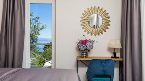 A hotel room with a bed, a desk with a chair, a mirror, and a view of the outdoors. - Beautiful home in Icici (Icici)