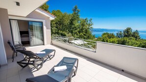 A balcony with two lounge chairs and a table, overlooking a scenic view of trees and a body of water. - Beautiful home in Icici (Icici)