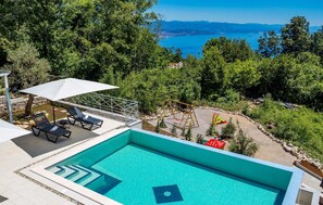 A swimming pool with a view of a lake and mountains, surrounded by trees and equipped with lounge chairs and an umbrella. - Beautiful home in Icici (Icici)