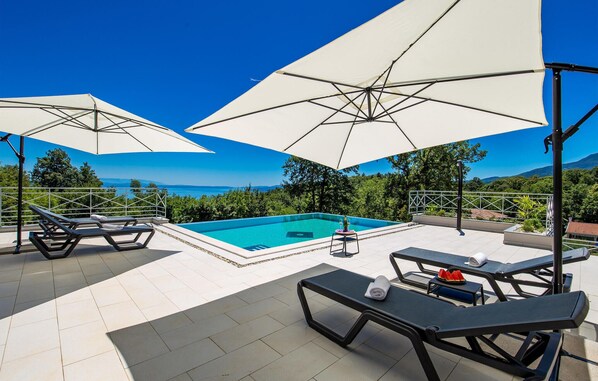 Relax by the pool with a view of the sea and surrounding landscape.