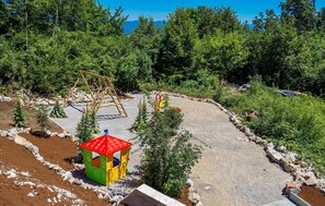 Relax in a serene outdoor space with a play structure, swing set, and shaded area.