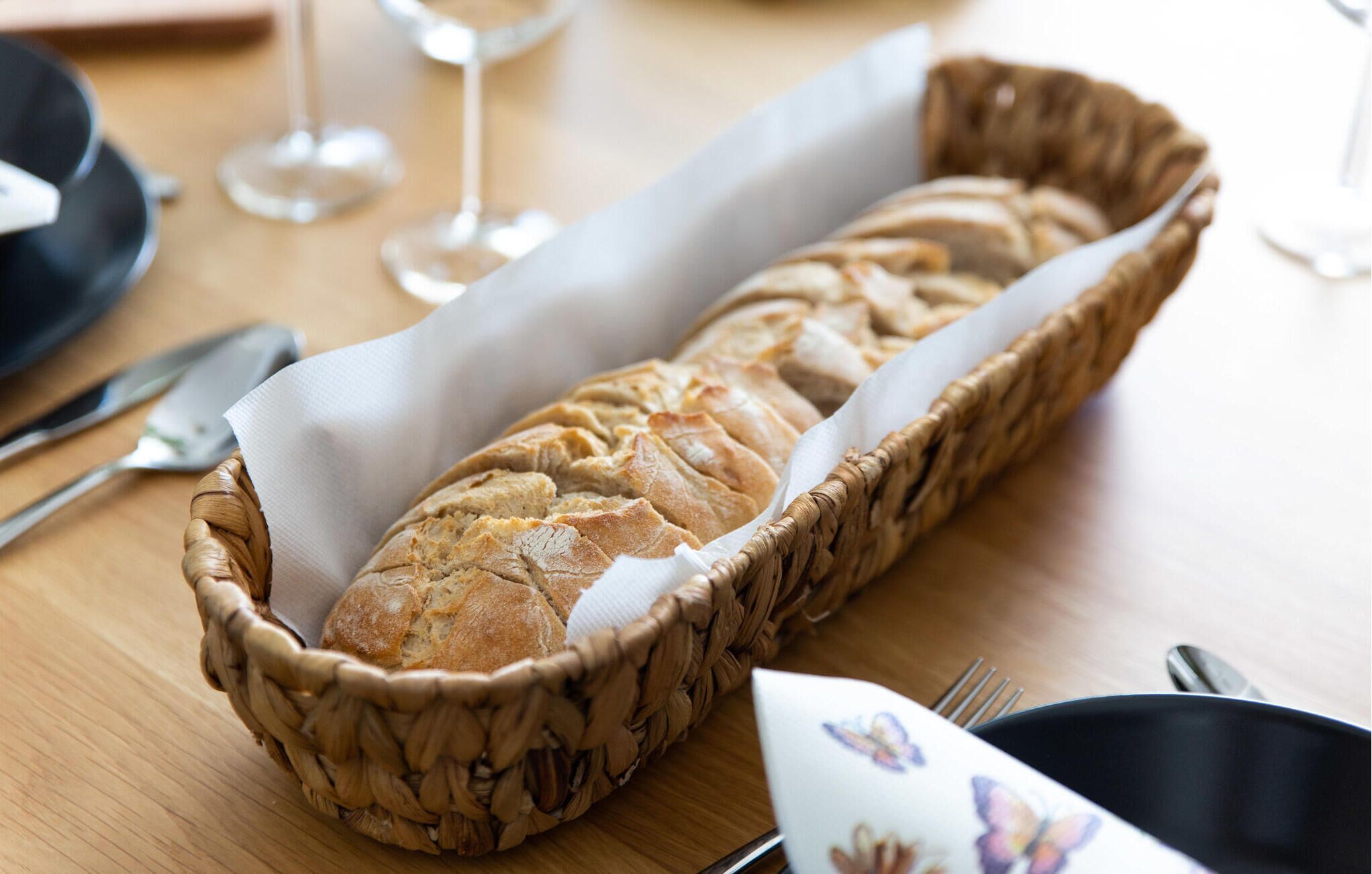 Une miche de pain dans un panier tressé, posée sur une table en bois.
