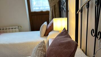 Une chambre d’hôtel avec deux lits, chacun doté d’un matelas texturé et d’un oreiller marron. Une lampe de chevet est posée sur l’un des lits.